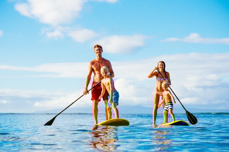 Father, mother and two sons on paddle boards outside the marina on an around the world cruise ship