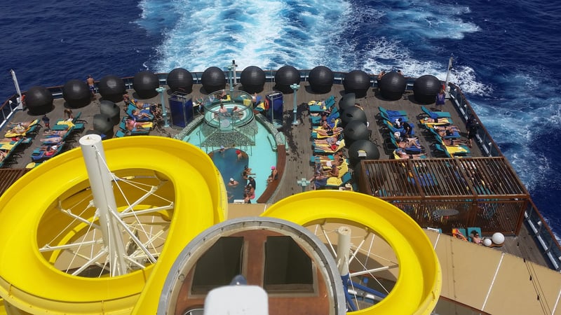 Crowded pool and deck of a cruise ship, tourists competing for deckchairs