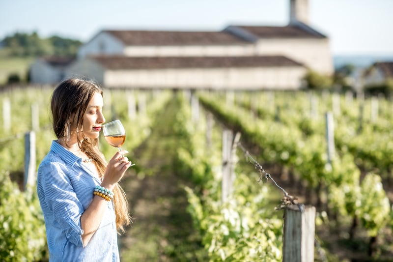 Young woman tasting wine on the vineyard in Bordeaux