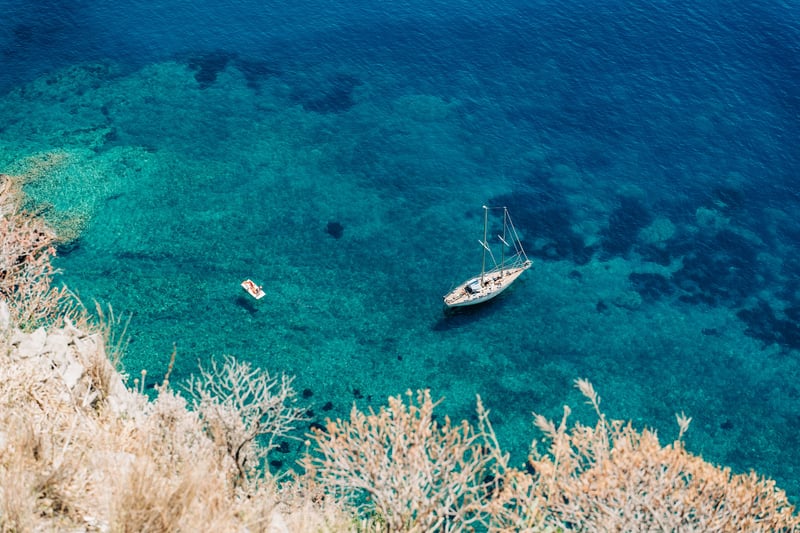Expat living on a yacht anchored in a Mediterranean cove with crystal clear azure waters