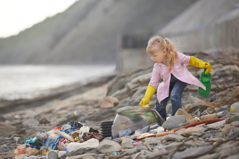 Little janitor picking up garbage at the beach