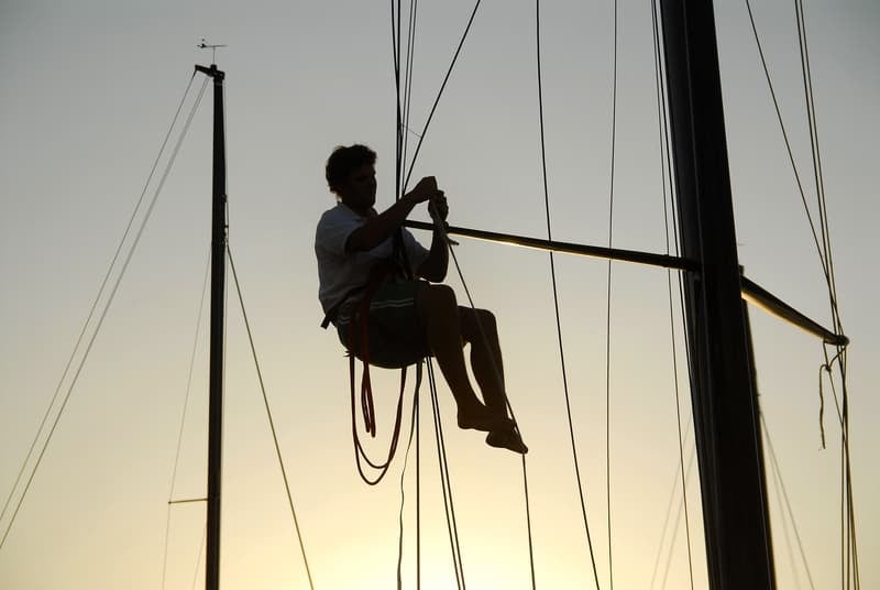 Man up mast of yacht fixing shit