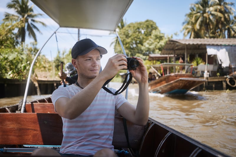 Solo traveler taking a photo on a boat on a river in Thailand 