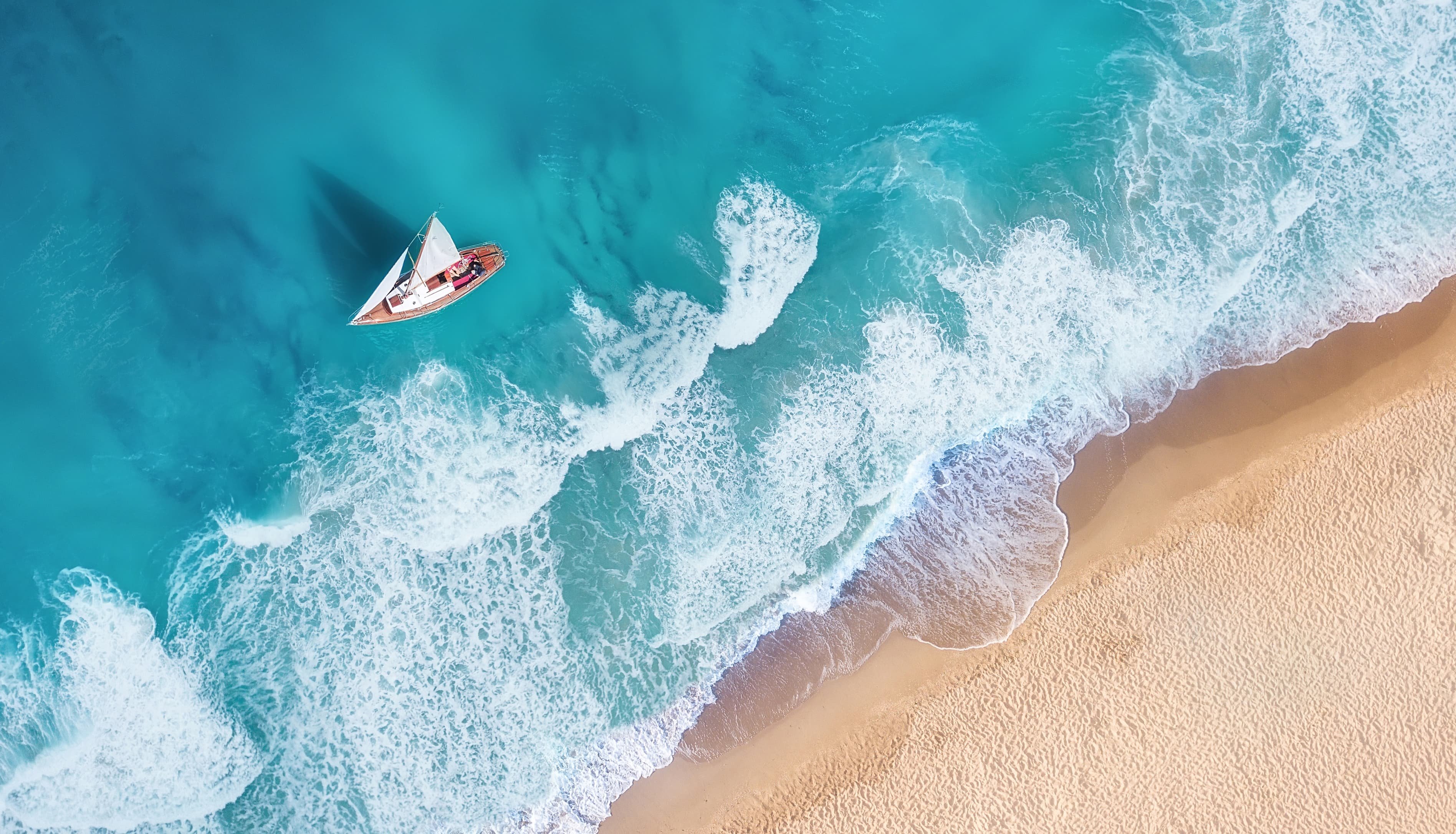Birds eye view of a yacht past the breakers off the beach