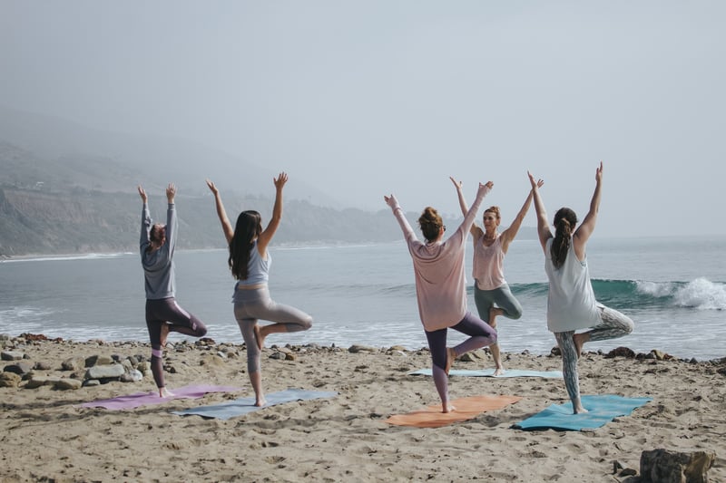 Woman doing yoga on beach as part of their wellness and longevity program